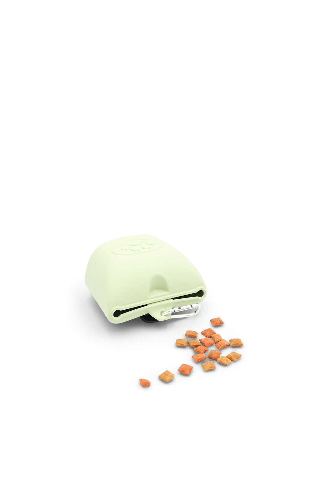 A pale yellow-green pet lick mat toy with a few small orange food pieces scattered in front, photographed on a clean white background.