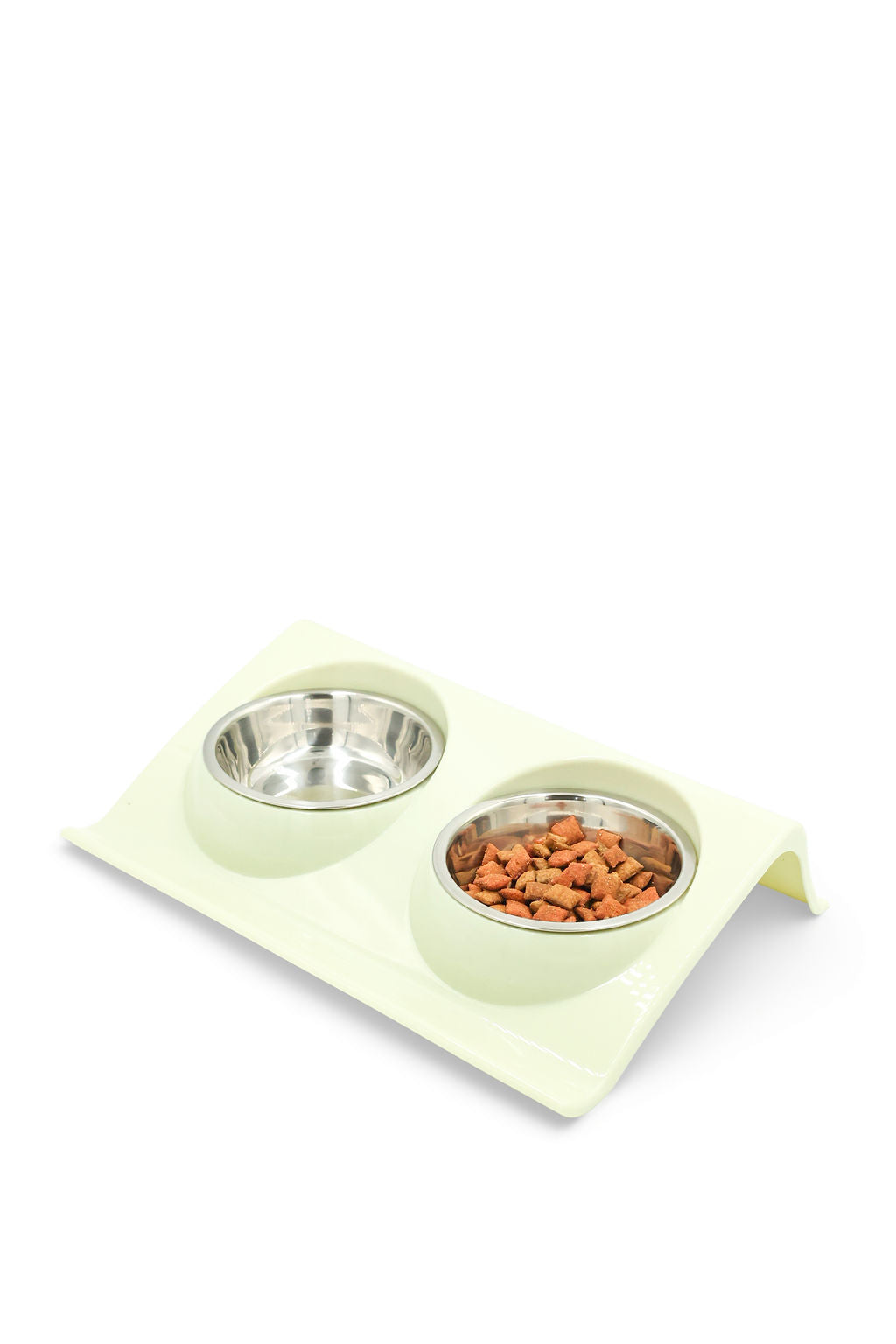 A light green elevated double pet feeder with two stainless steel bowls, one empty and one filled with dry kibble, on a white background.