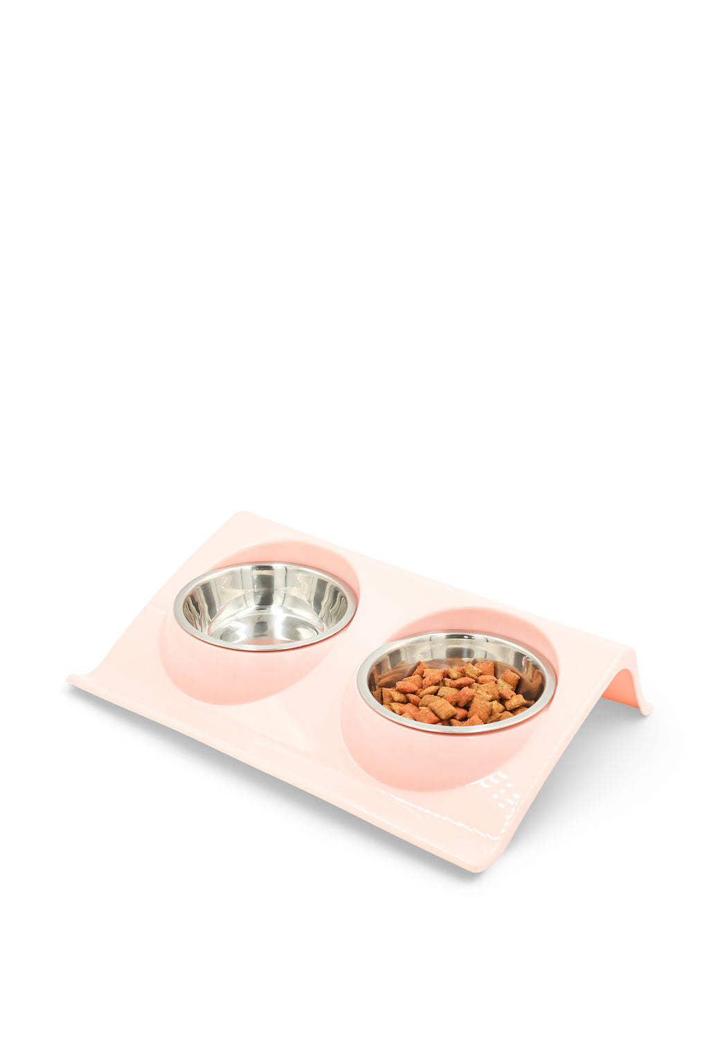 A pink elevated double pet feeder with two stainless steel bowls, one empty and one filled with dry dog food, on a clean white background.