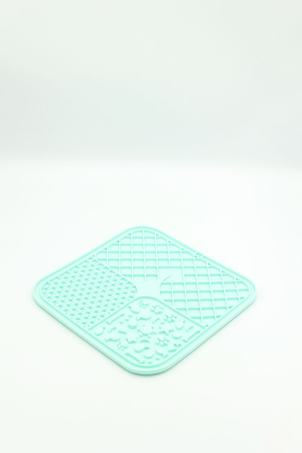 A mint green silicone pet lick mat with four textured sections, photographed on a clean white background.