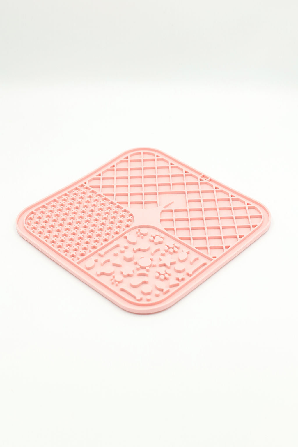 A pink silicone pet lick mat with four textured sections, shown on a clean white background.