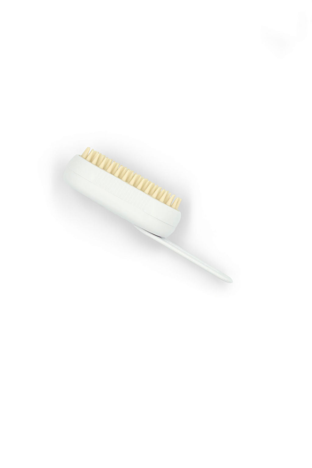 A white handheld facial cleansing brush with beige bristles, shown diagonally on a clean white background.
