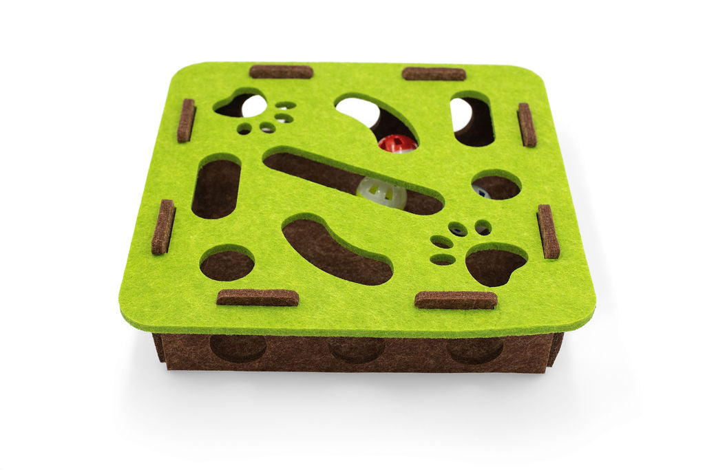 Top-down view of the green felt maze layout showing cutout paw tracks and treat slots for cat play.